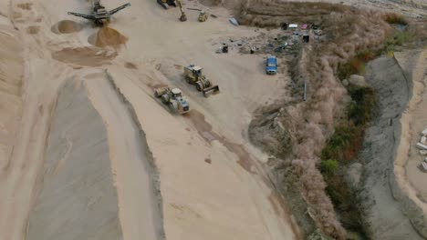 Vista-Aérea-En-Movimiento-De-La-Excavadora-Trabajando-En-Una-Cantera-De-Roca-Conduciendo-Por-El-Sitio