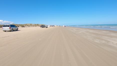 POV-thru-driver's-window-while-on-beach-with-vacationing-families-on-gulf-side-of-South-Padre-Island,-Texas