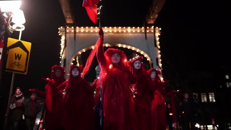 Rebeldes-Rojos-Con-Amigos-Holandeses-De-La-Tierra-Vestidos-De-Rojo-Marchando-Por-La-Calle-Por-La-Noche---Protesta-Por-El-Cambio-Climático-Contra-Shell-En-La-Haya-Y-Ámsterdam,-Países-Bajos---Rebelión-De-Extinción