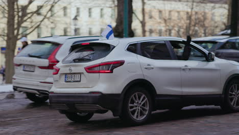 Waving-hands-and-national-flags-in-a-car-window-on-the-streets-of-Helsinki,-Finland---Olympic-Ice-hockey-championship-celebrations