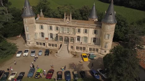 Vista-Aérea-De-Drones-De-Una-Exposición-De-Autos-Antiguos-Frente-A-Un-Castillo