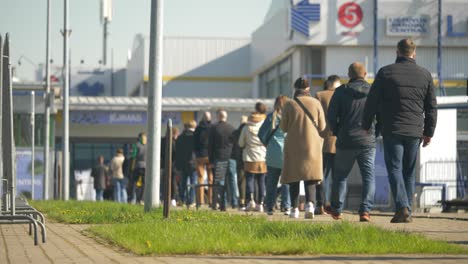 Toma-En-Cámara-Lenta-Desde-La-Parte-Posterior-De-Las-Personas-De-Pie-En-La-Fila-De-Vacunación