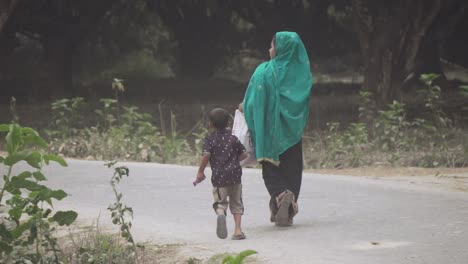 Mujer-Junto-A-Su-Hijo-Caminando-Por-Un-Camino-De-Pueblo