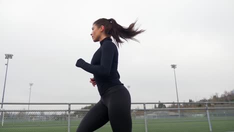 Mujer-Deportiva-En-Ropa-Deportiva-Negra-Corriendo-En-La-Pista,-Exterior-Slomo