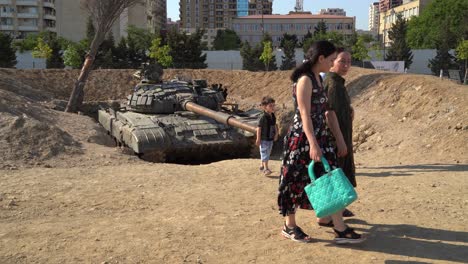 Familia-Azerbaiyana-Mira-El-Tanque-Armenio-Capturado-En-Trophy-Park,-Bakú,-Azerbaiyán