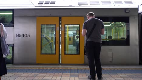 Transporte-Sydney-Trenes-Puerta-Cerrando-Y-Hombre-Esperando-El-Tren-En-La-Estación-Central-De-Trenes-De-Sydney,-Nueva-Gales-Del-Sur,-Australia