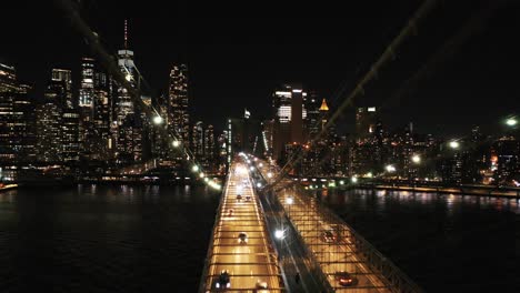 Eine-Langsame-Drohnenaufnahme-Der-Skyline-Von-New-York-Von-Der-Brooklyn-Bridge-Bei-Nacht