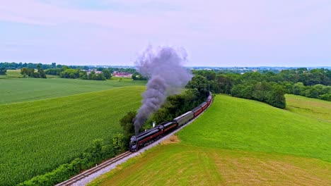 Una-Vista-Aérea-De-Un-Antiguo-Tren-De-Pasajeros-De-Vapor-Que-Sopla-Humo-Negro-A-Través-De-Las-Tierras-Agrícolas-De-Pensilvania