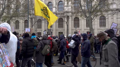 Gente-Ondeando-La-Bandera-De-Gadsen-Caminando-Por-La-Calle-Durante-Las-Protestas-Contra-La-Corona