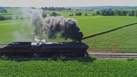 Paisaje-Aéreo-De-Tierras-De-Cultivo-Y-Un-Motor-De-Vapor-Antiguo-Pasa-A-Través-De-Los-Campos-De-Maíz-En-Una-Mañana-De-Verano-Temprano