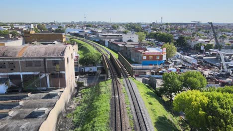 Following-the-train-tracks-on-a-bridge,-big-city-around,-aerial-shot