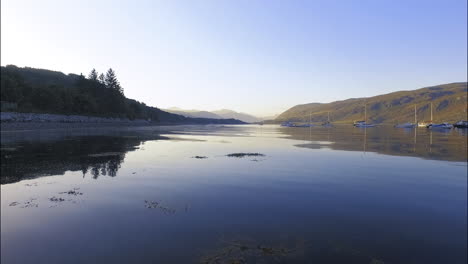 Hafen-Von-Ulapool-Mit-Segelbooten-Im-Loch-Broom,-Niedrige-Luftaufnahme-über-Dem-See