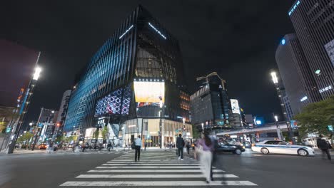 Menschen-überqueren-Die-Sukiyabashi-Kreuzung-Mit-Verkehr-In-Der-Nacht-Vor-Dem-Einkaufszentrum-Tokyu-Plaza-In-Ginza,-Tokio,-Japan