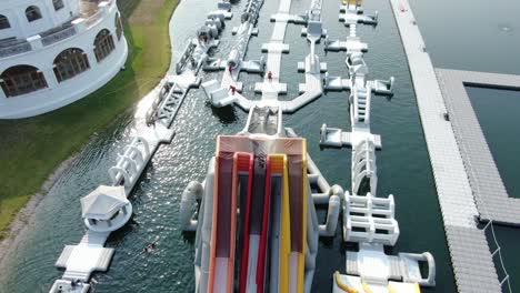 People-enjoying-a-sunny-day-at-Hong-Kong-core-aqua-park-floating-fun-slides,-Aerial-view