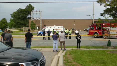 Group-of-people-watching-rescue-team-working-at-crash-area-covered-in-yellow-tape