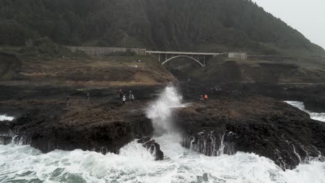 A-large-wave-erupts-out-of-Thor's-Well-at-Cape-Perpetua,-Oregon-coast,-aerial