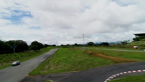 racing-track-with-grass-and-asphalt-and-grey-jaguar-ipace-car-aerial