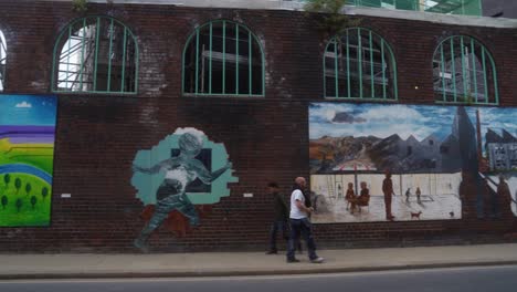 Handheld-panning-shot-of-men-walking-in-opposite-directions-down-a-street-in-Kelham-Island