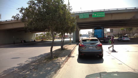 Tráfico-Diurno-En-Una-Calle-Bulliciosa-En-Tijuana,-México-Con-Hombre-Cruzando