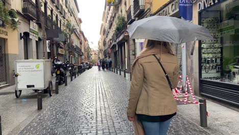 Clip-De-4k-De-Una-Niña-Caminando-Tranquilamente-En-Medio-Del-Centro-De-La-Ciudad-De-Madrid-En-Un-Día-Lluvioso