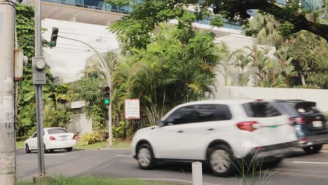 Shot-from-a-curb-of-a-sidewalk-as-motor-vehicles-pass-through-a-suburban-traffic-intersection,-Panama-City