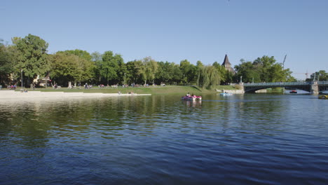 Couple-enjoy-peaceful-peddle-boat-on-lake-in-Budapest,-Hungary