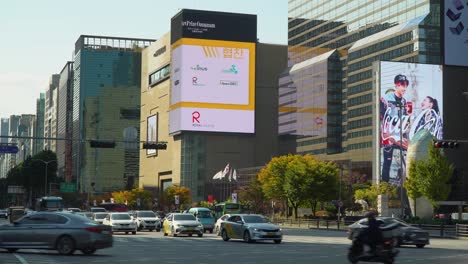 Cars-start-turning-on-green-traffic-light-on-Teheran-ro-Road-in-Seoul-near-Grand-Intercontinental-Hotel-COEX,-Hyundai-Department-Store,-Samseong-Station-in-Autumn,-Huge-Outdoor-Wall-Ad-Billboards