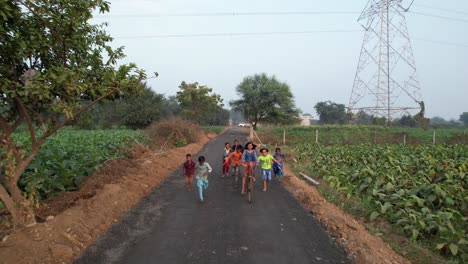 Niño-Indio-En-Bicicleta-Corriendo-Vista-Aérea,-Camino-De-Aera-De-Pueblo,-Aspecto-Vintage,-Vida-De-Pueblo-Indio-Antena-2