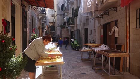 Alte-Frau-Auf-Einem-Straßenstand,-Der-Produkte-In-Einer-Engen,-Schönen-Straße-In-Bari,-Italien,-Verkauft