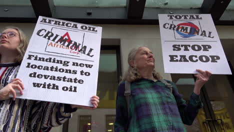 Dos-Manifestantes-Contra-El-Cambio-Climático-Sostienen-Pancartas-En-Las-Que-Llaman-&quot;criminales&quot;-A-Las-Empresas-De-Petróleo-Y-Energía-Total-De-África-Fuera-Del-Hotel-Mayfair-Durante-La-Cumbre-De-Energías-De-África