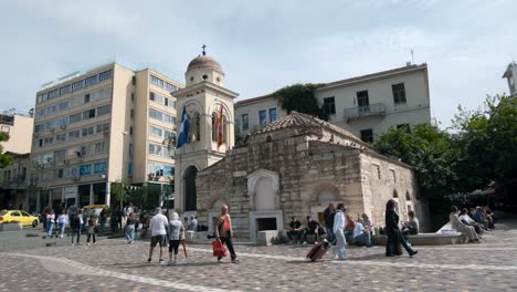 Toma-Panorámica-De-Los-Edificios,-La-Iglesia-Panagia-Pantanassa-Y-La-Gente-En-La-Plaza-Monastiraki.