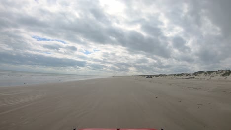 POV-A-Través-Del-Parabrisas-Del-Vehículo-Que-Conduce-En-La-Playa-Entre-El-Surf-Y-Las-Dunas-De-La-Costa-Nacional-De-North-Padre-Island-Cerca-De-Corpus-Christi,-Texas,-EE.UU.-En-Un-Día-Nublado