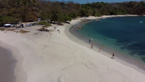 Playa-De-Arena-Blanca-De-San-Juanillo-En-Costa-Rica,-La-Gente-Nada-Y-Toma-El-Sol-En-La-Playa