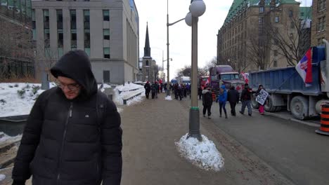 Grandes-Multitudes-De-Manifestantes-Canadienses-Caminando-A-Lo-Largo-De-Camiones-Estacionados,-Protestando-Por-Los-Mandatos-Del-Virus-De-La-Corona