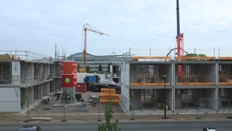 Arbeiter-Und-Kräne-Bewegen-Sich-Im-Zeitraffer-Und-Verteilen-Baumaterial-Dort,-Wo-Es-Benötigt-Wird,-Auf-Der-Baustelle-Puur12-Vor-Einem-Blauen-Himmel-Mit-Sich-Bildenden-Und-Vorbeiziehenden-Wolken