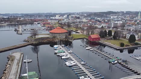 Puerto-Deportivo-De-Christianholm-Y-Fortaleza-De-Kristiansand-En-El-Centro-De-La-Ciudad---Antena-Ascendente-En-Movimiento-Hacia-Adelante-Desde-El-Puerto-Deportivo-Para-Revelar-Una-Vista-Completa-De-La-Ciudad-Hacia-El-Oeste-Hacia-Hannevika---Noruega