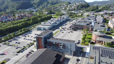 Centro-Comercial-Asane-Arken-Y-Alrededores-Cerca-De-La-Autopista-E39-Que-Conduce-A-Bergen-Noruega---Vista-Aérea-De-Día-Soleado-Con-Fondo-De-Montaña-Exuberante