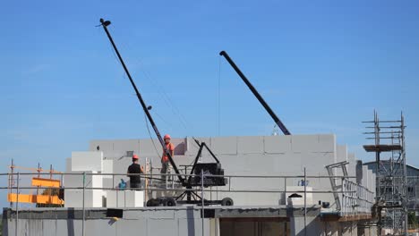 Lapso-De-Tiempo-De-La-Pared-De-Apoyo-Que-Construyen-Los-Trabajadores-De-La-Construcción-Con-Una-Pequeña-Grúa-Y-Grandes-Ladrillos-Blancos-Prefabricados-Contrastados-Con-El-Cielo-Azul-Parte-Del-Desarrollo-Urbano-Del-Barrio-De-Noorderhaven