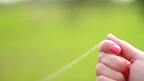 Woman's-hand-is-holding-a-kite-rope-being-stretched-strong-in-one-moment-and-than-released-back