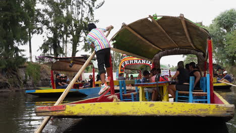 Gondoliere-Schieben-Mit-Einem-Hölzernen-Ruderruder-Die-Gondel,-Die-Touristen-Entlang-Der-Xochimilco-Kanäle-Transportiert