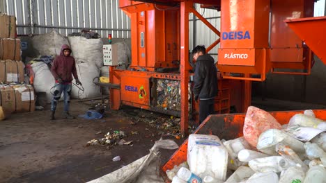 Ein-Bulldozer-Bereitet-Sich-Darauf-Vor,-Von-Zwei-Arbeitern-In-Einer-Abfallverarbeitungsanlage-Mit-Verdichtetem-Müll-Beladen-Zu-Werden