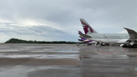 Ver-Cámara-Lenta-Dentro-De-La-Bahía-De-Estacionamiento-Del-Aeropuerto-Con-Un-Avión-Boeing-Mientras-La-Carga-Del-Servicio-Terrestre-Opera-En-Un-Día-De-Lluvia