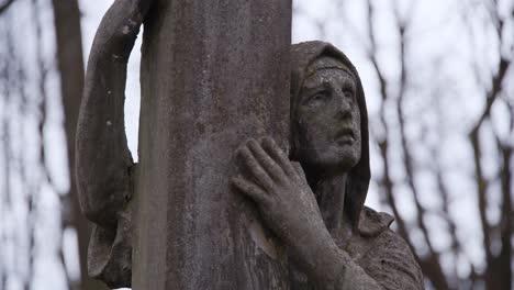 Alte-Steinstatue-Der-Mutter-Maria,-Bedeckt-Mit-Moos,-Die-Sich-An-Einer-Steinsäule-Festhält