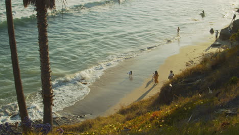 People-on-the-shoreline,-joyful-children-playing-with-the-water