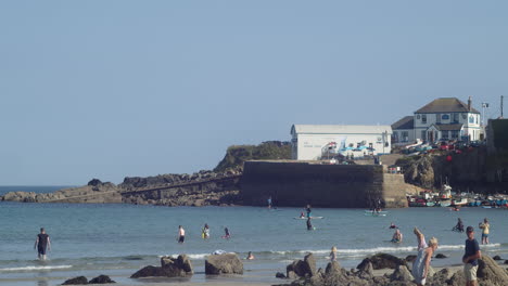 Playa-De-Coverack-En-Verano-Con-Turistas-Jugando-Y-Remando-De-Pie