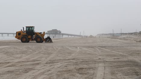 Caterpillar-930m-Radlader-Nutzt-Die-Schaufel,-Um-An-Einem-Nebligen-Morgen-Den-Sand-Am-White-Cap-Beach-Auf-North-Padre-Island-Zu-Ebnen