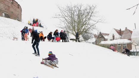 Niños-Y-Padres-En-Trineo-En-Un-Burcht-Nevado-En-Leiden,-Países-Bajos-Durante-La-Pandemia