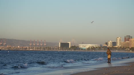 A-man-fishing-on-the-Beach-and-the-Long-Beach-skyline-in-the-background---slow-motion