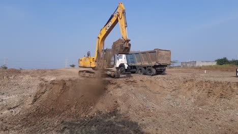 Ein-Bagger-Lädt-Auf-Der-Baustelle-Sandmoorum-In-Einen-Muldenkipper