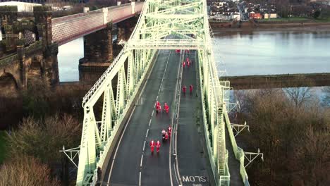 Charity-Santa-dash-fun-run-over-Runcorn-Silver-Jubilee-bridge-Aerial-view-slow-pan-shot-down